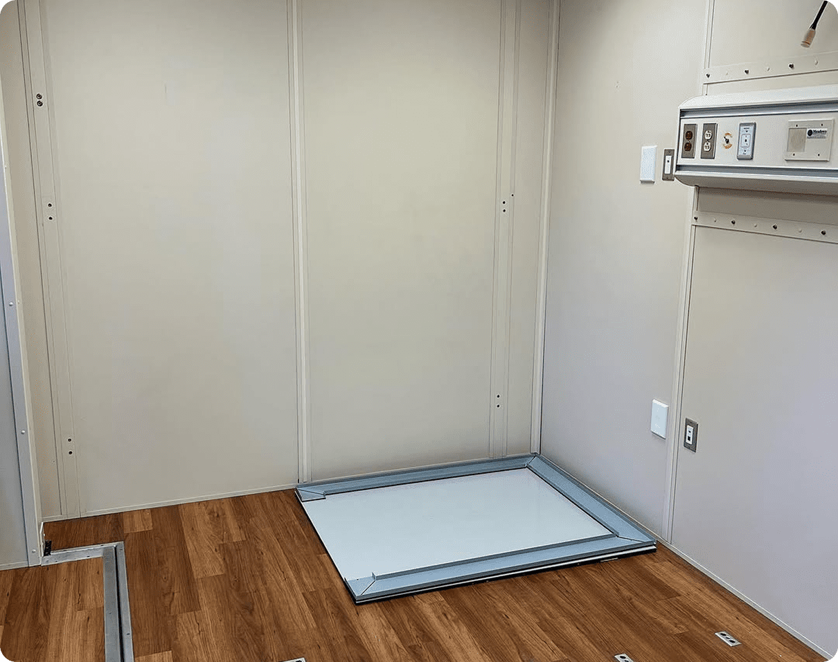 Room with a wooden floor and white walls, and a metal frame on the floor