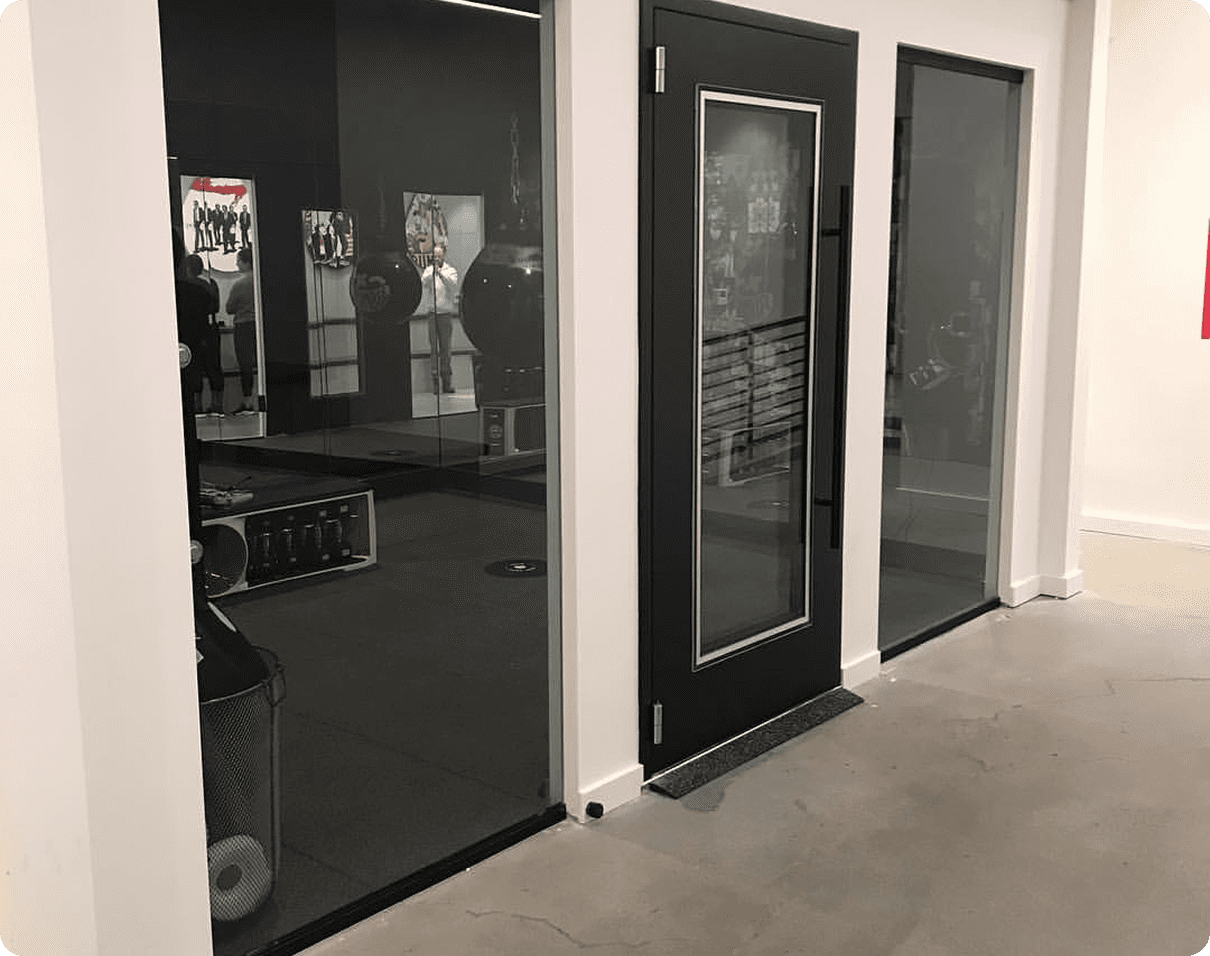 Black and white photo of a room with a glass door and a red sign on the wall
