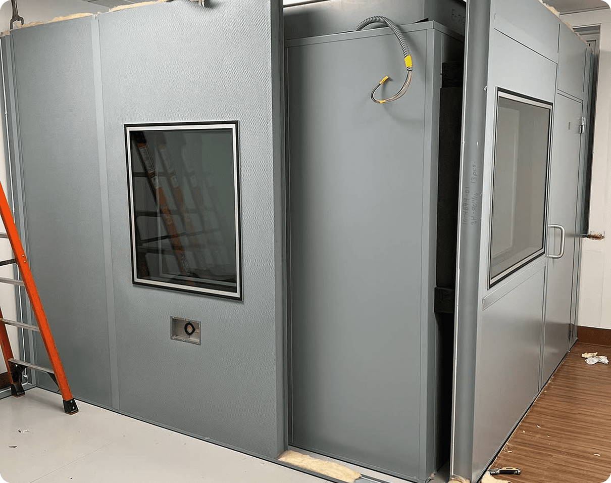 Room with a ladder and a door in it, as well as a wall with a window and a pipe